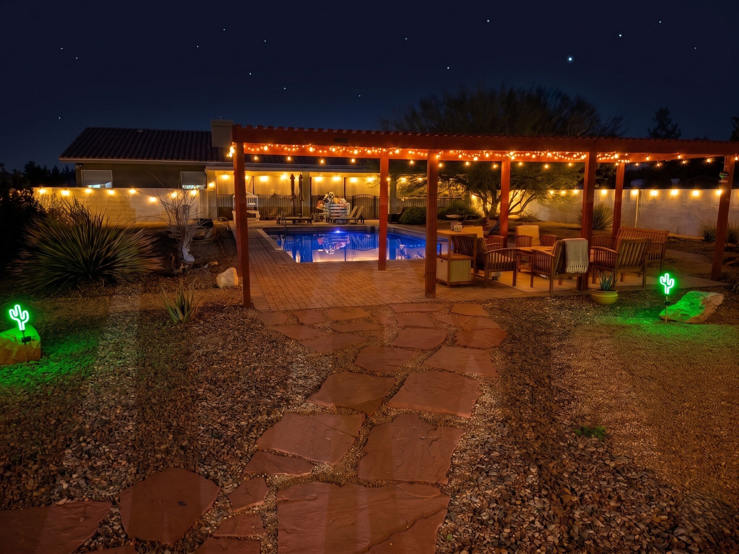 A backyard with a pool, patio furniture, and string lights.