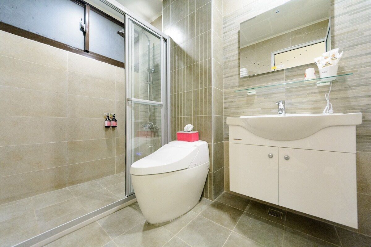 A modern bathroom with a glass shower enclosure, a white toilet, and a vanity with a mirror.