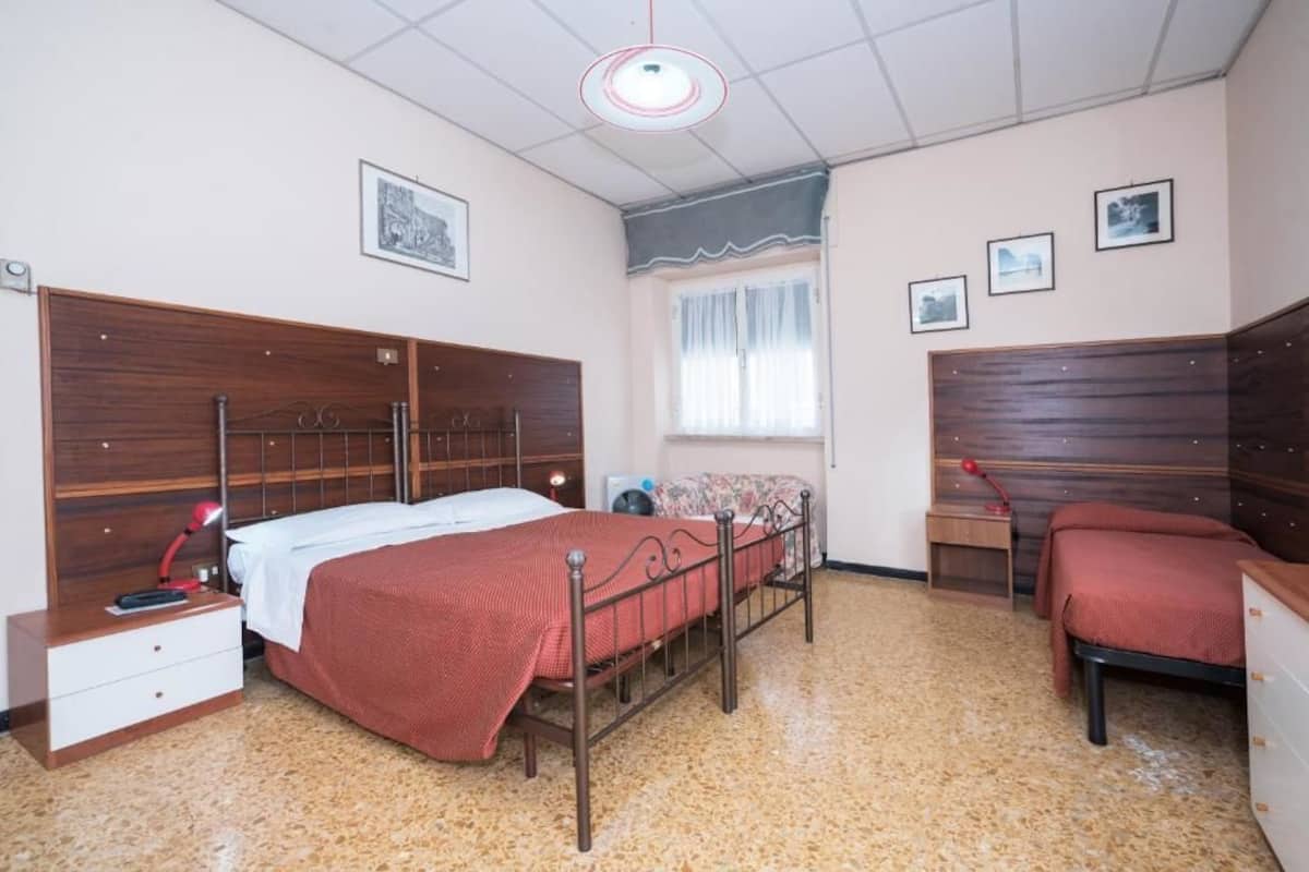 A bedroom with a wooden bed, a nightstand, a desk, and a chair.