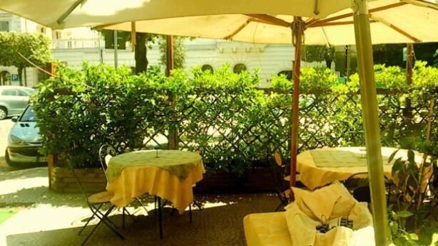An outdoor patio with tables and umbrellas, surrounded by greenery and trees. - Albergo Ristorante Stella (Palestrina)