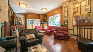 A hotel lobby with leather sofas, a coffee table with flowers, wooden flooring, and framed pictures on the walls. - Albergo Ristorante Stella (Palestrina)