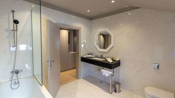 A modern bathroom with a glass-enclosed shower, a black sink, and a white toilet.