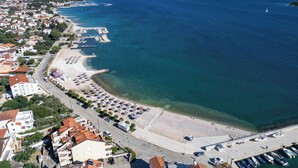 Vista aérea de un pueblo costero con playa, puerto deportivo y edificios residenciales.