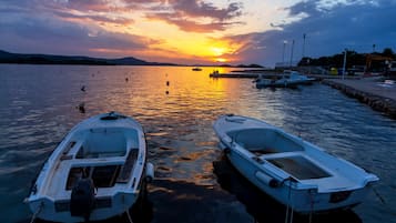 Two boats docked at a marina with a sunset in the background.