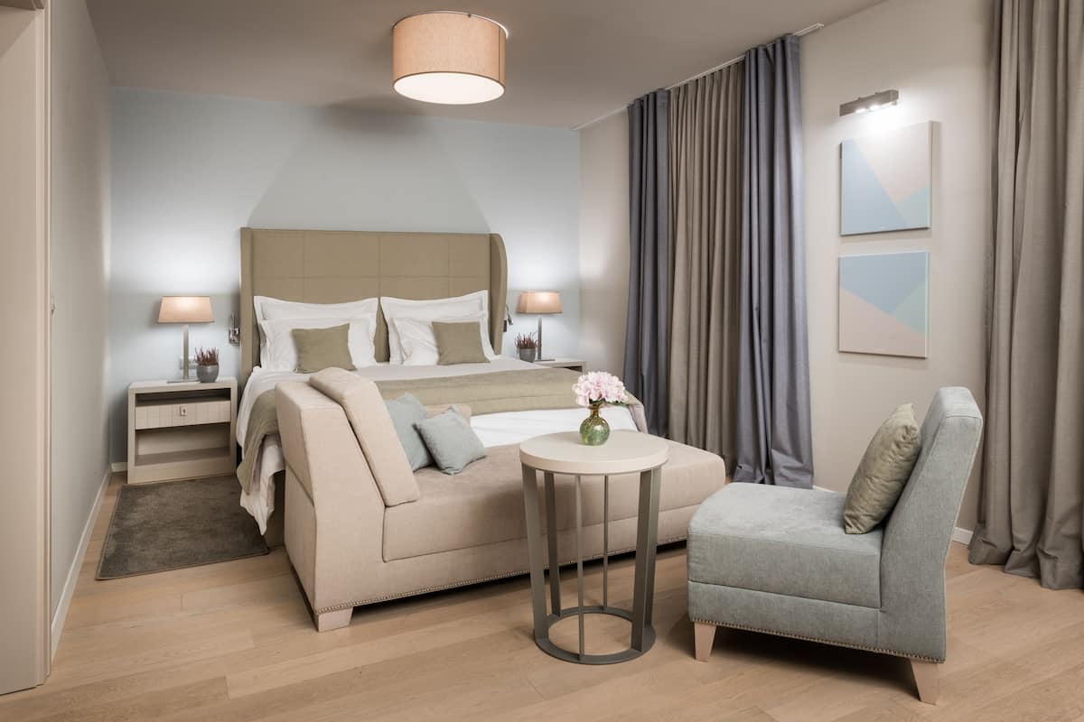 Una habitación de hotel moderna con una cama, un sofá, una mesita y una silla.