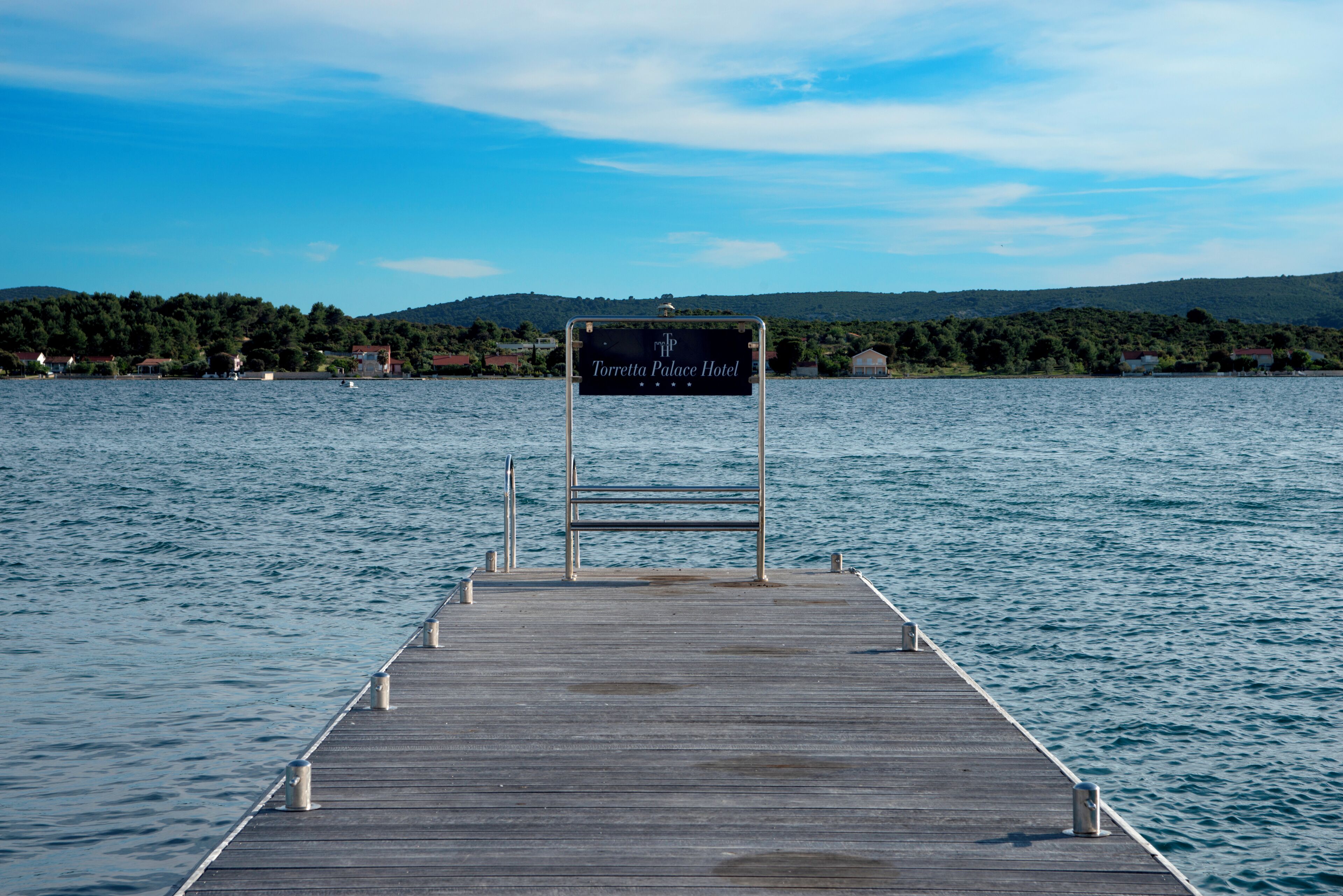A wooden pier leading to a sign for Torretta Palace Hotel.