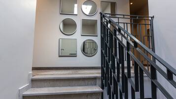 A staircase with a metal railing and a wall with multiple mirrors.