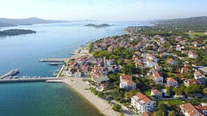 Vue aérienne d’une ville côtière avec des immeubles résidentiels, une marina et des eaux d’un bleu limpide.