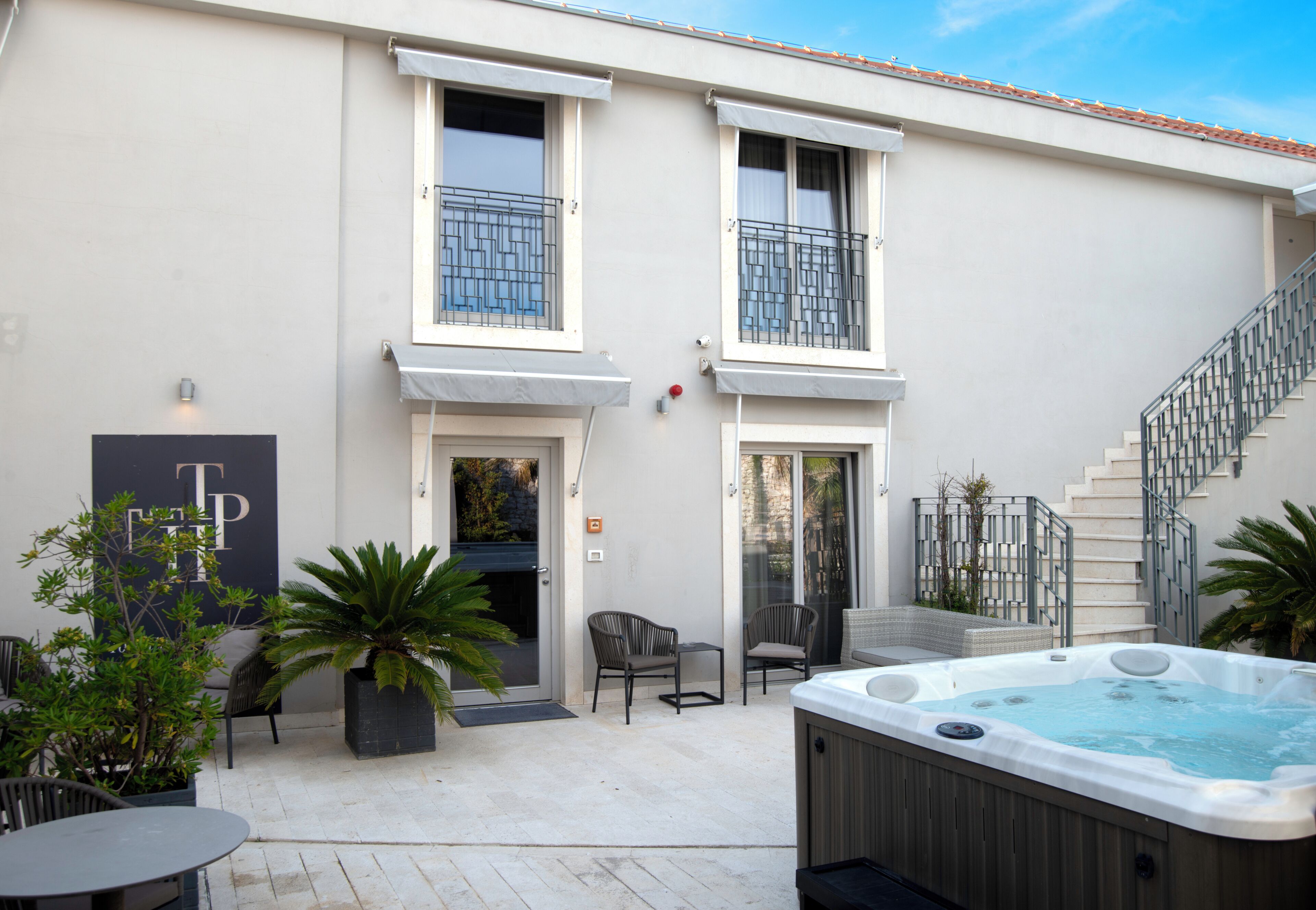 Un bâtiment doté d’un patio, d’un espace extérieur aménagé avec des sièges, d’un jacuzzi et d’un escalier.