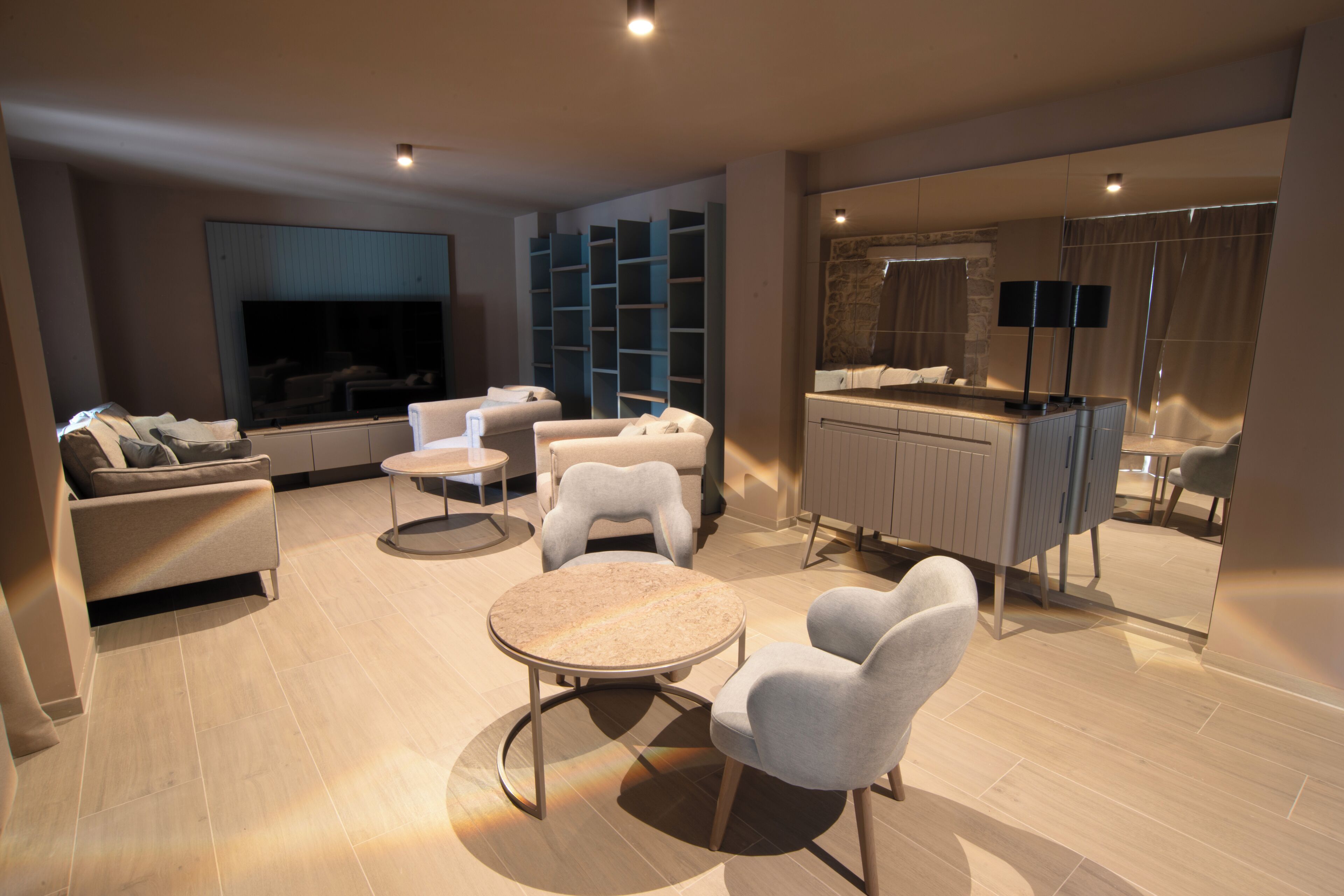 Una sala de estar moderna con sofá, sillas, una mesa de centro, televisor y una zona de cocina con mostrador y armarios.
