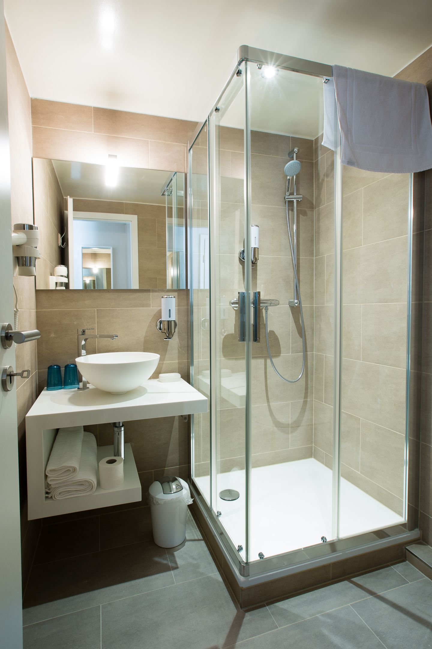 A modern bathroom with a glass-enclosed shower, a white sink, and a mirror above the sink.