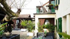 A courtyard with outdoor seating, potted plants, and a tree.
