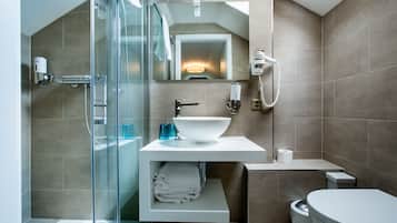 Een moderne badkamer met een douchecabine van glas, een witte wastafel en een toilet.