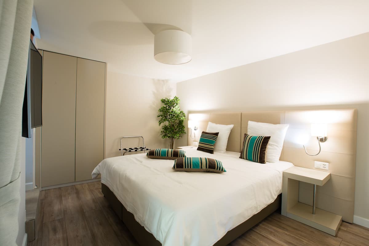 Un dormitorio moderno con una cama grande, mesitas de noche, un armario y una planta colgante.