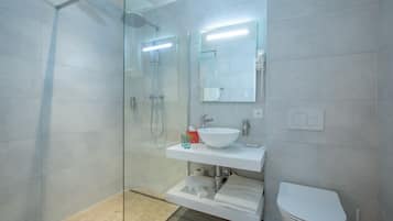 Ein modernes Badezimmer mit einer Duschkabine, einem weißen Waschbecken und einer Toilette.