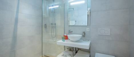 Un bagno moderno con doccia in vetro, lavandino bianco e water.