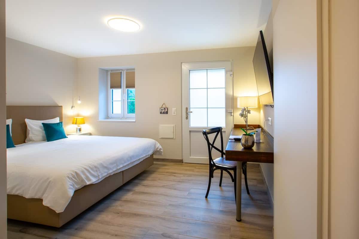Un dormitorio con cama, mesita de noche, lámpara y ventana.