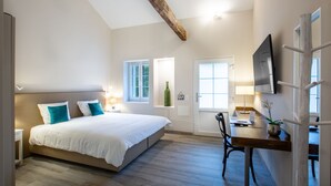 A bedroom with a bed, bedside tables, a desk with a chair, a TV, and a window.