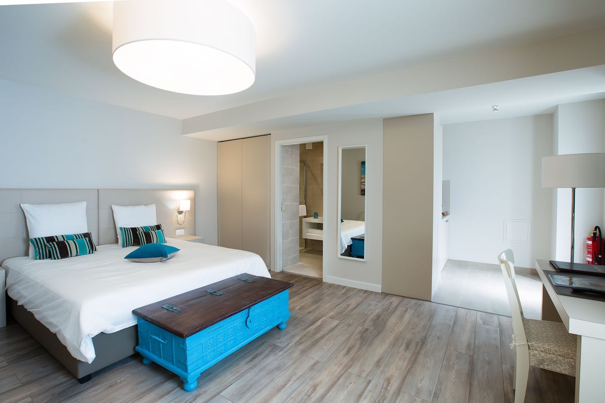 Una habitación de hotel moderna con una cama grande, un escritorio y un baño visible a través de una puerta abierta.