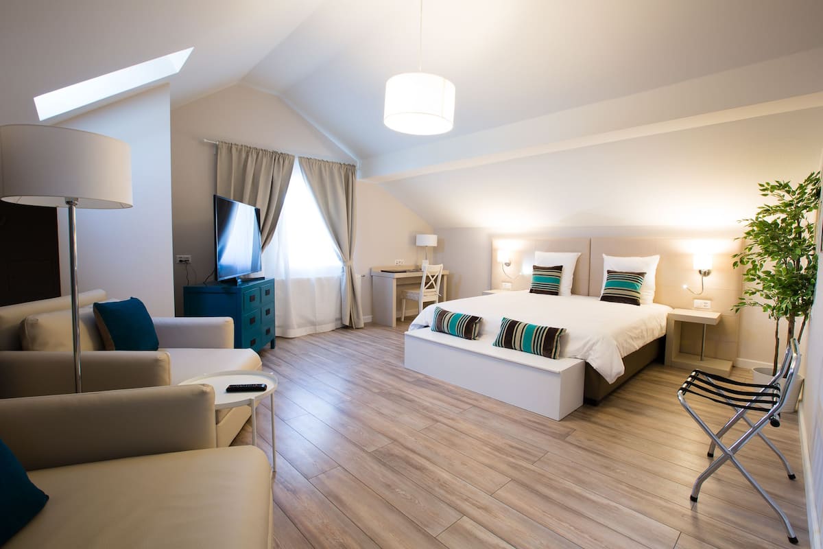 Una habitación de hotel moderna con una cama grande, un sofá, un televisor y un escritorio.