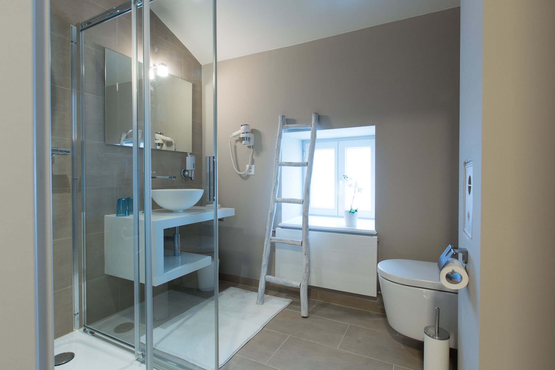 A modern bathroom with a glass shower enclosure, a white sink, and a toilet.