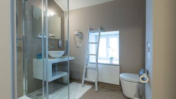 A modern bathroom with a glass shower enclosure, a white sink, and a toilet.