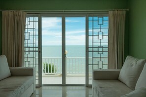 A room with a large sliding glass door leading to a balcony with a view of the sea. There are two white sofas in the room. - Gao Phala (Ban Chang)