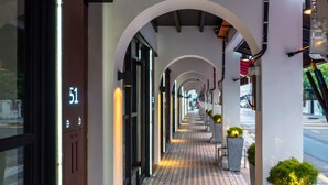 A corridor with a patterned floor, arched ceiling, and a row of potted plants. - Macallum Central Hotel Managed By The Ascott Limited (George Town)