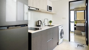A modern kitchen with a stainless steel refrigerator, a microwave, a kettle, and a washing machine. - Macallum Central Hotel Managed By The Ascott Limited (George Town)