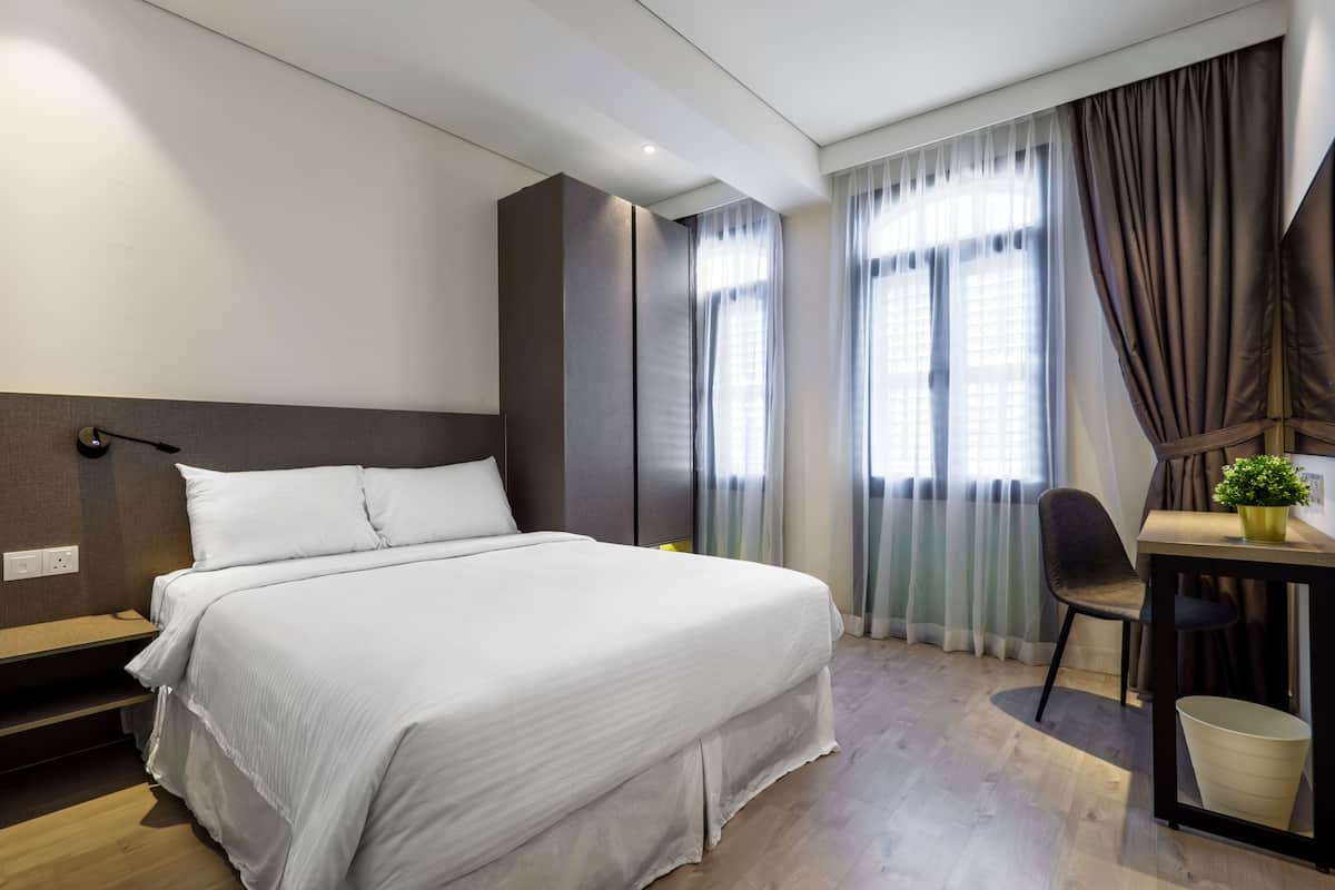 A modern hotel room with a large bed, a desk, and a chair.