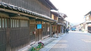 A traditional Japanese street with wooden buildings, a sidewalk with flower boxes, and a clear road. - GUESTHOUSE YANAGIYA - Hostel (Ena)