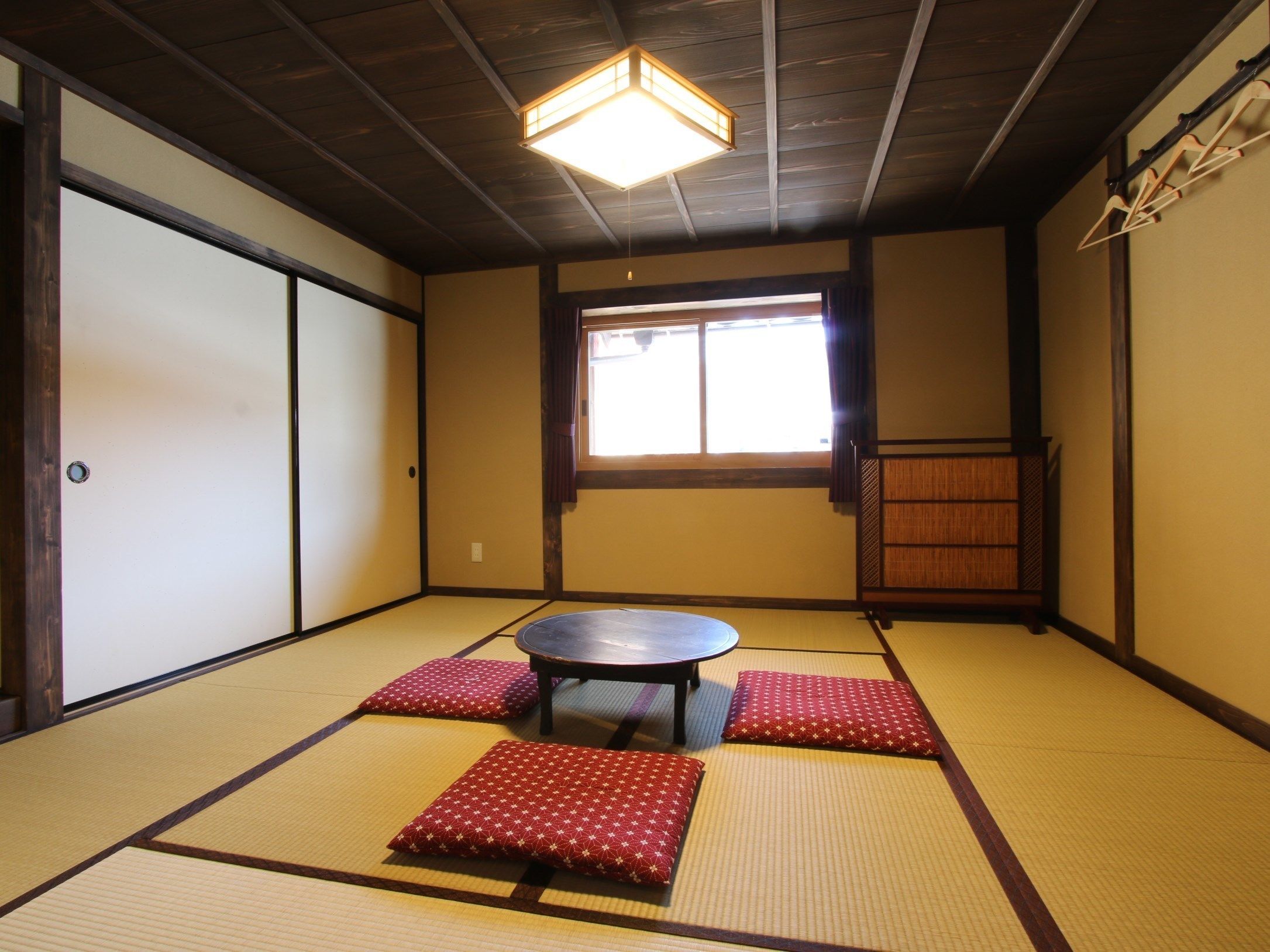 Una stanza con tatami, un tavolo in tatami, cuscini, una porta scorrevole e una finestra con vista.