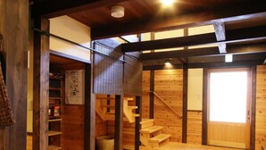 A wooden interior with a staircase leading to a loft area, a door with a window, and a shelf with items. - GUESTHOUSE YANAGIYA - Hostel (Ena)