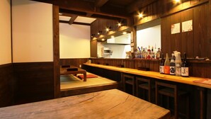 A traditional Japanese bar with wooden furnishings, a long counter, and a seating area with tatami mats. - GUESTHOUSE YANAGIYA - Hostel (Ena)