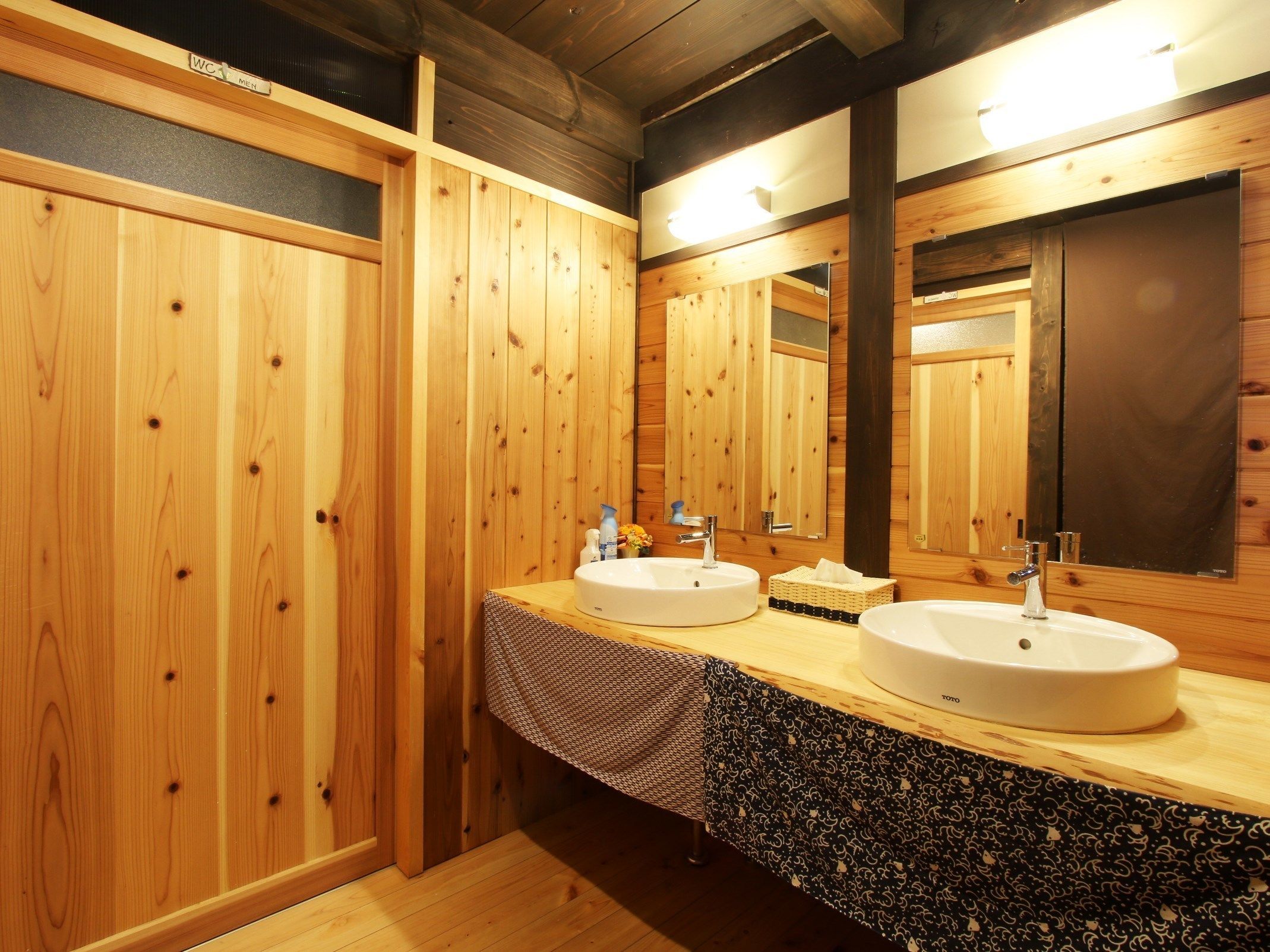 A wooden bathroom with two sinks, a mirror, and a towel rack.