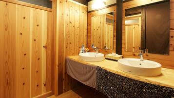 A wooden bathroom with two sinks, a mirror, and a towel rack.