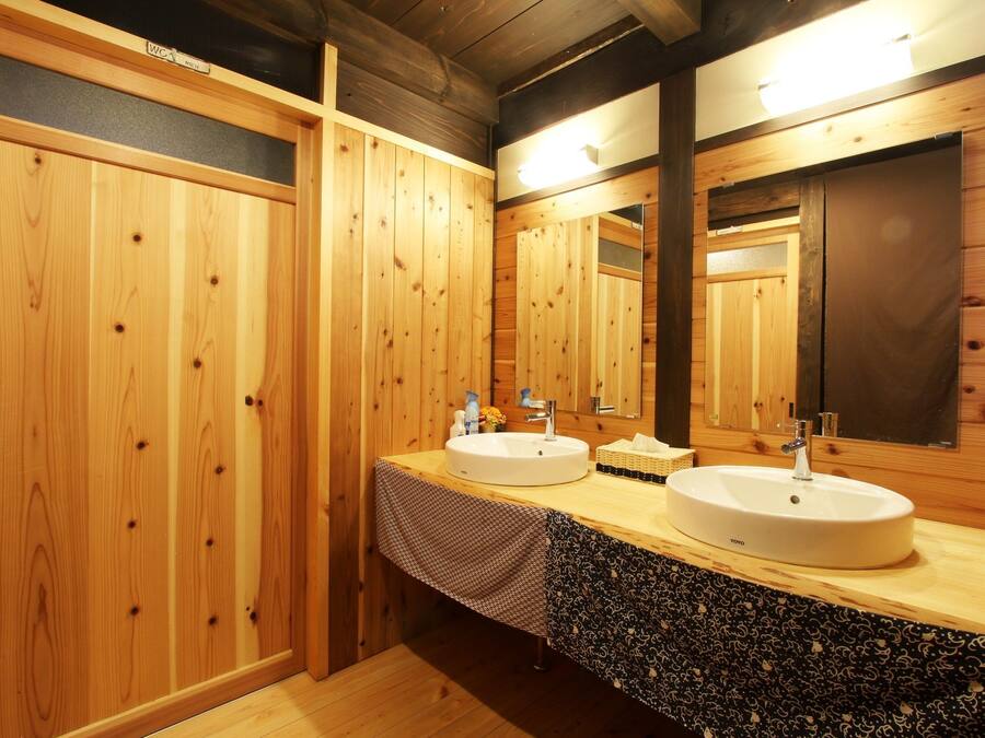 A wooden bathroom with two sinks, a mirror, and a towel rack.