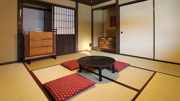 A tatami mat room with a low table and cushions, wooden sliding doors, and a traditional Japanese-style lamp. - GUESTHOUSE YANAGIYA - Hostel (Ena)