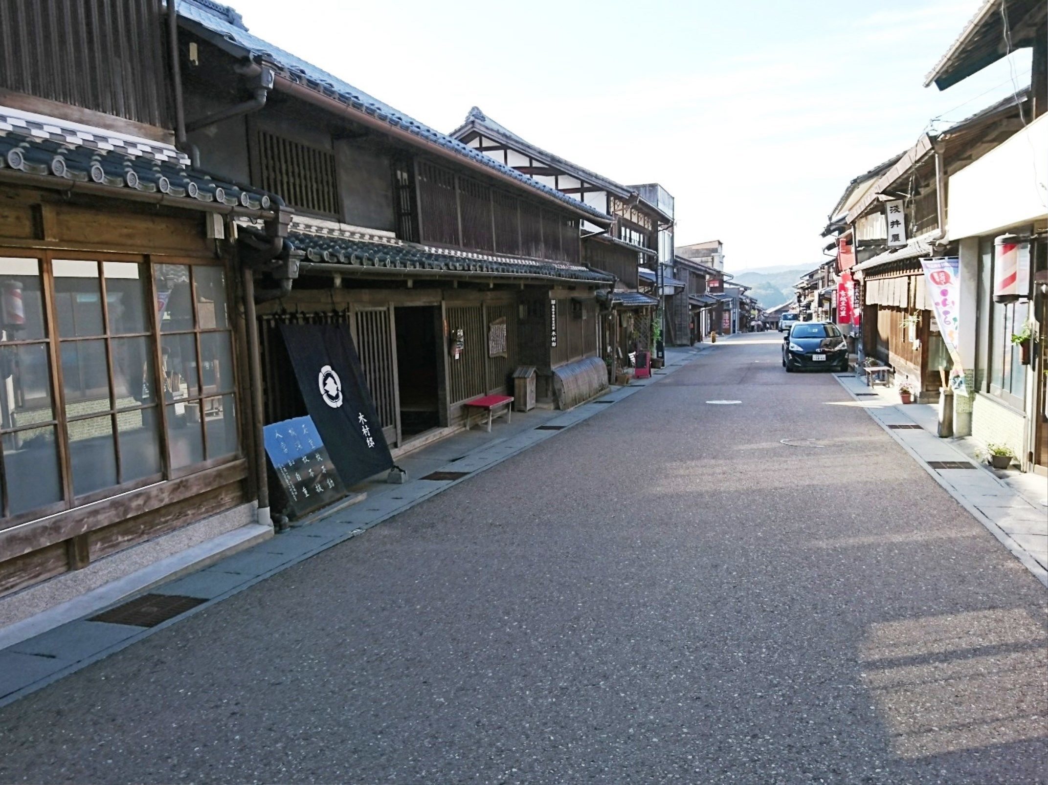 A narrow street lined with traditional wooden buildings, some with signage indicating local businesses.