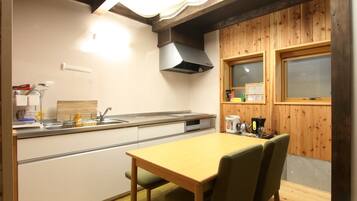 A compact kitchen with a wooden table and chairs, a sink, and a window with blinds.