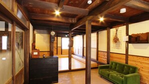A traditional Japanese interior with tatami flooring, a green sofa, wooden beams, and a clock on the wall. - GUESTHOUSE YANAGIYA - Hostel (Ena)