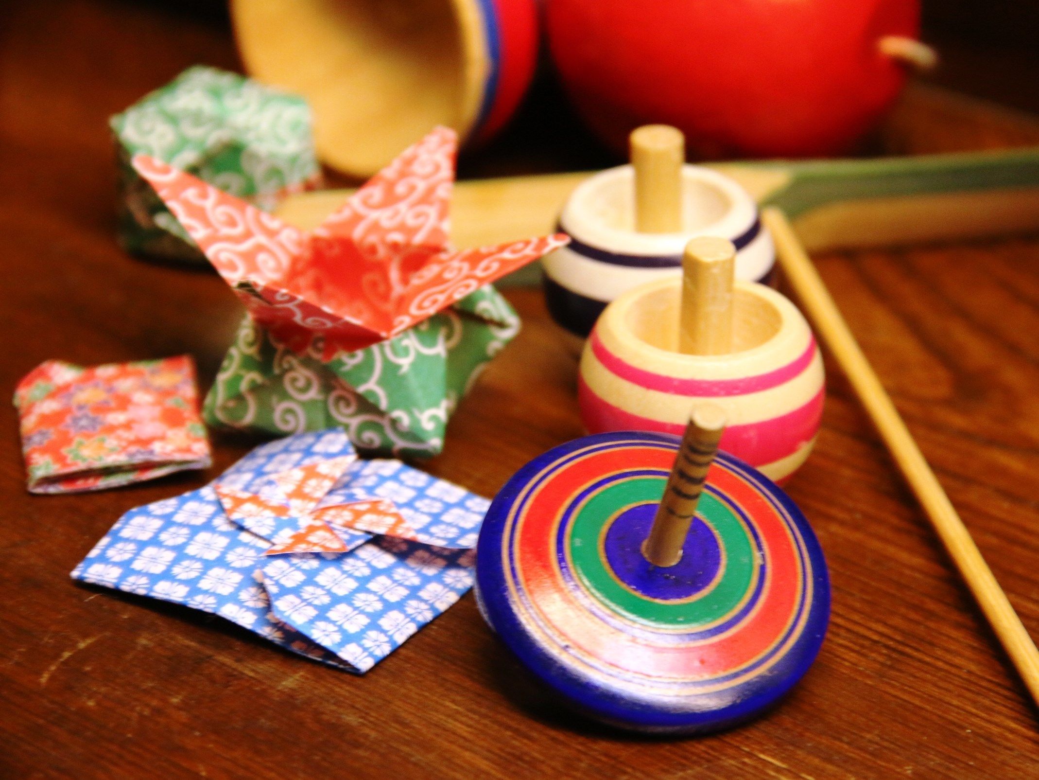 Una mesa de madera con un trompo y un pequeño juguete, ambos girando.