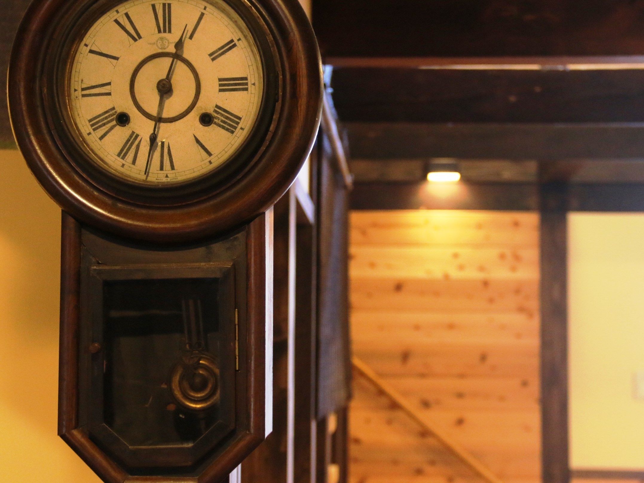 A close-up of a wall-mounted analog clock with Roman numerals.