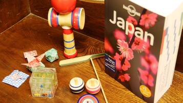 Ett träbord med en utdragbar karta med japanskt tema, en leksak i trä, origamikonst och en plastbehållare.