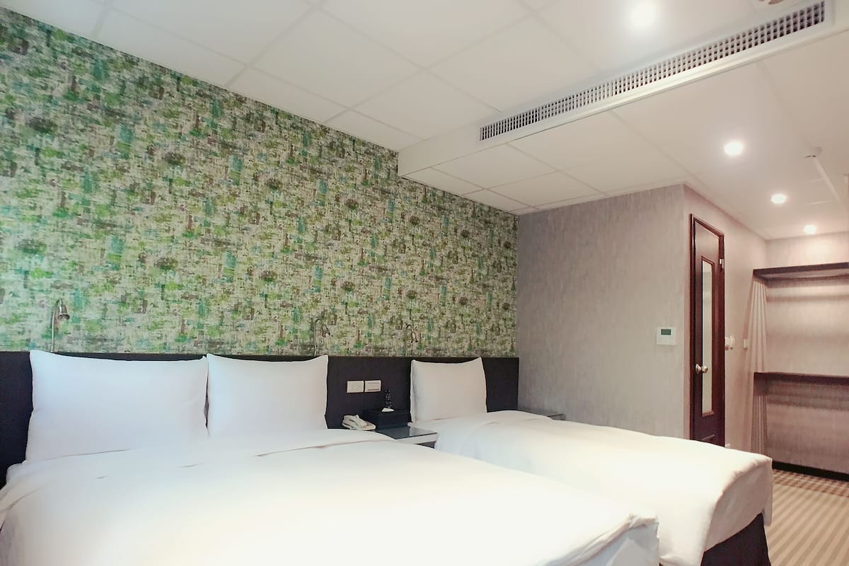 A hotel room with a large bed, a headboard, a nightstand, a mirror, and a door.
