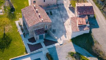 An aerial view of a property with a swimming pool, a large building with a tiled roof, and a smaller adjacent structure.