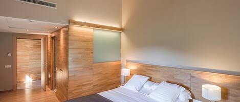 Een moderne hotelkamer met een groot bed, bedlampen, een houten hoofdeinde en een kledingkast.