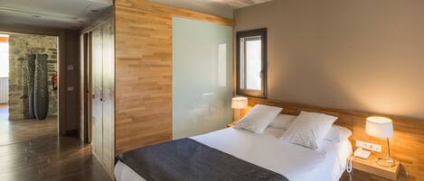 A hotel room with a wooden bed, two bedside lamps, a large mirror, and a stone wall.