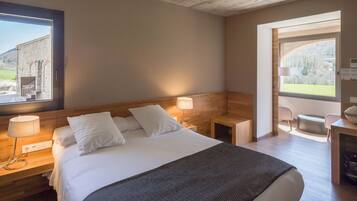 Una habitación de hotel moderna con una cama grande, cabecera de madera, lámparas de noche y vistas al exterior.