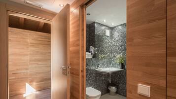 Un baño moderno con tocador de madera, lavamanos y retrete.